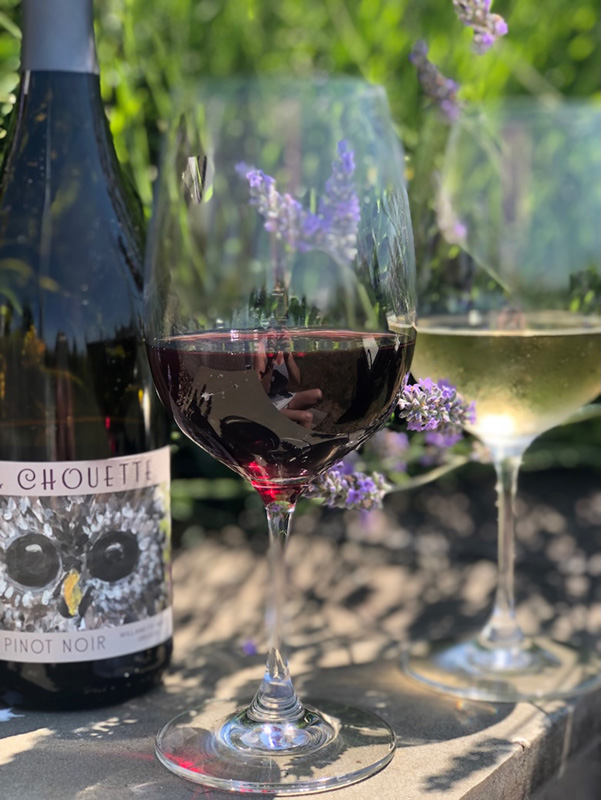 Bottle of La Chouette wine with two glasses of white, one red, one white